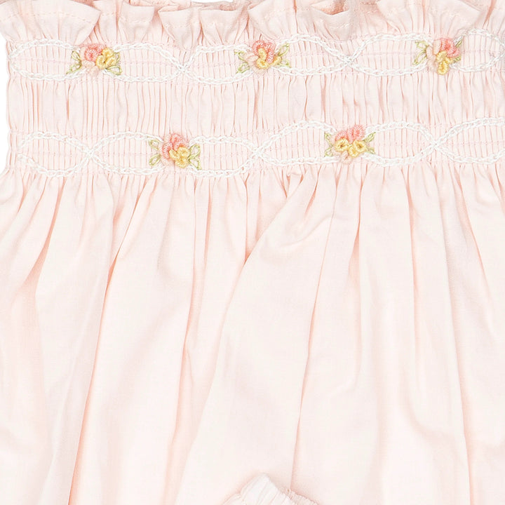 Hand-smocked flutter tunic with embroidered details and matching bloomers in soft pink on a white background.