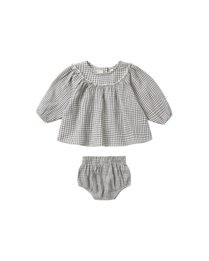 This darling organic set in a deep blue gingham is thoughtfully designed with a full gathered blouse, delicate ruffle details, and soft balloon sleeves, finished with a button-back closure for easy dressing