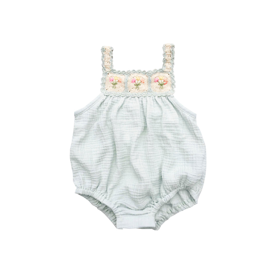 Baby romper with floral lace top on a white background