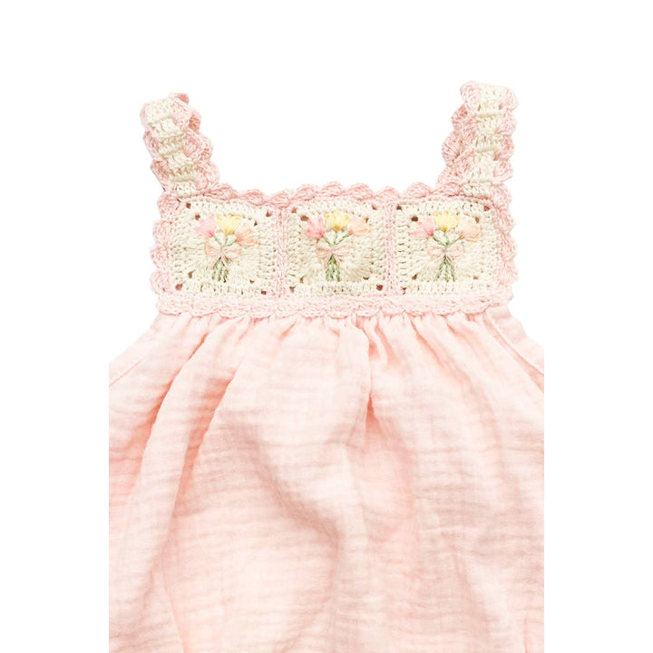 Pink baby romper with floral lace details on a white background