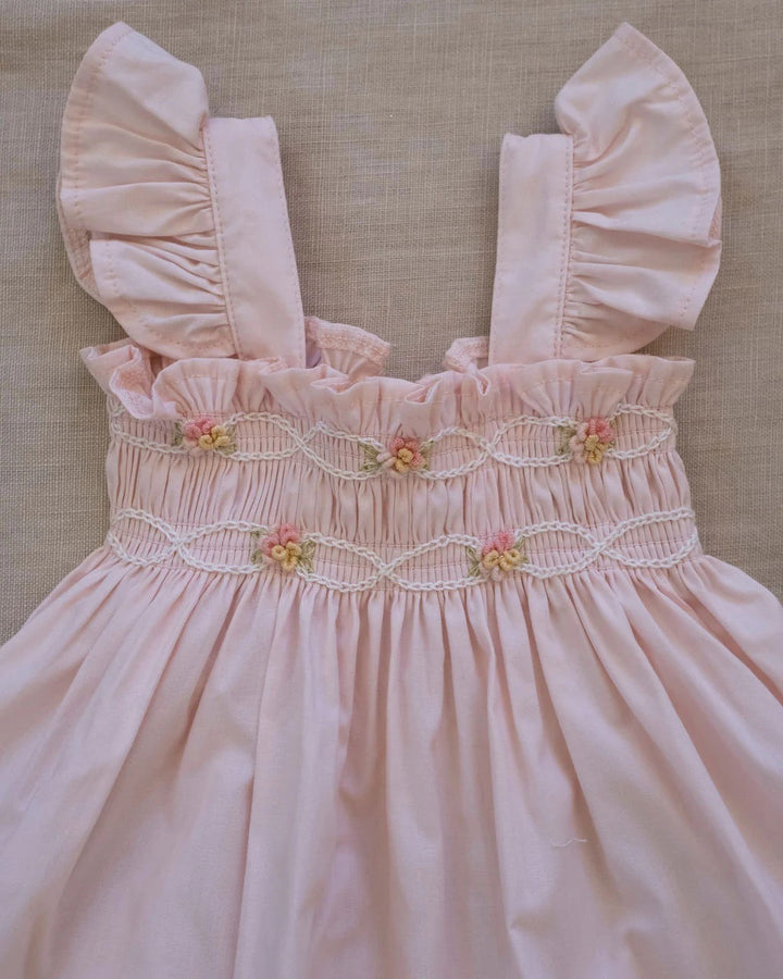 Hand-smocked flutter tunic with embroidered details and matching bloomers in soft pink on a white background.